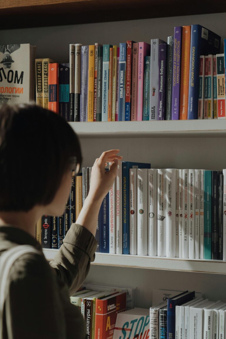 A person browsing a diverse bookshelf, highlighting learning and leisure in a library.