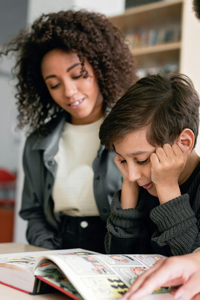 A child reading a book with a supportive teacher in a modern classroom environment.